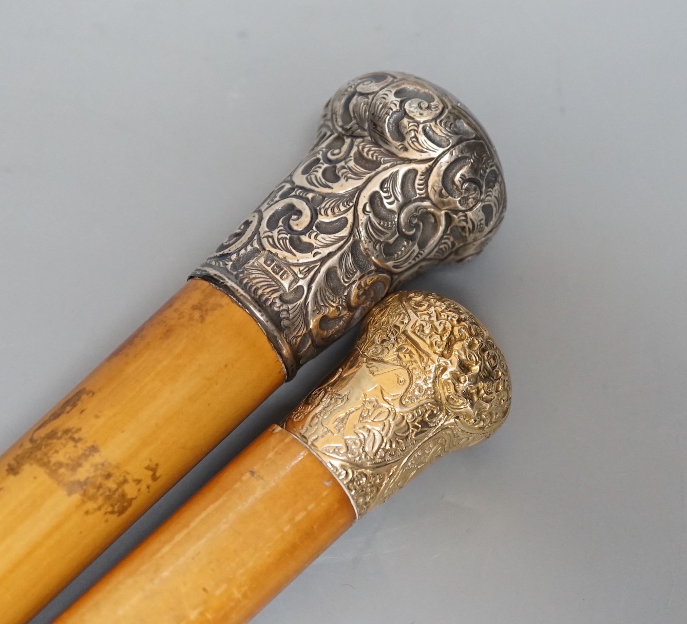 Two 19th century malacca walking canes: one with an Indian inspired 9ct gold handle, the other with a silver embossed handle, gold handled cane 92 cms long